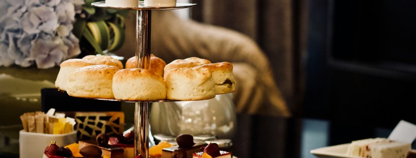 High Tea Services with scones, sandwiches and tea cups on a low table.