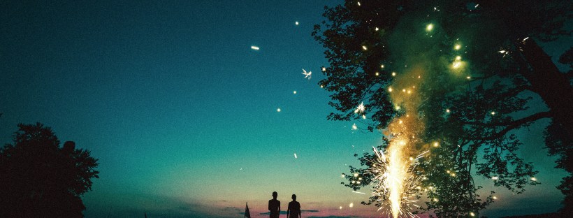 Night sky and fireworks with a couple watching in the distance